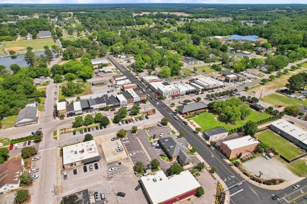 Wide aerial view of downtown Angier, North Carolina showing the central business district with nearby lake, neighborhoods, and tree-lined landscape.