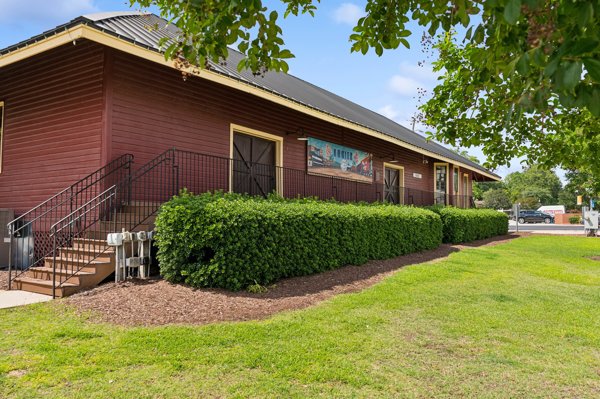 Exterior view of a historic-style building and green space in Angier, North Carolina town center with landscaped hedges and walkway.