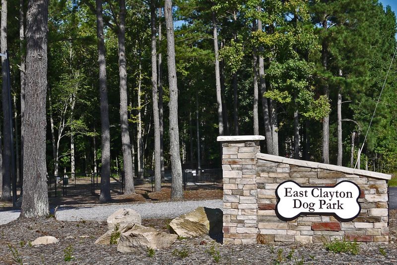 East Clayton Dog Park entrance sign and fenced wooded park area