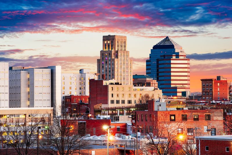 Downtown Durham skyline at sunset with illuminated buildings and city lights