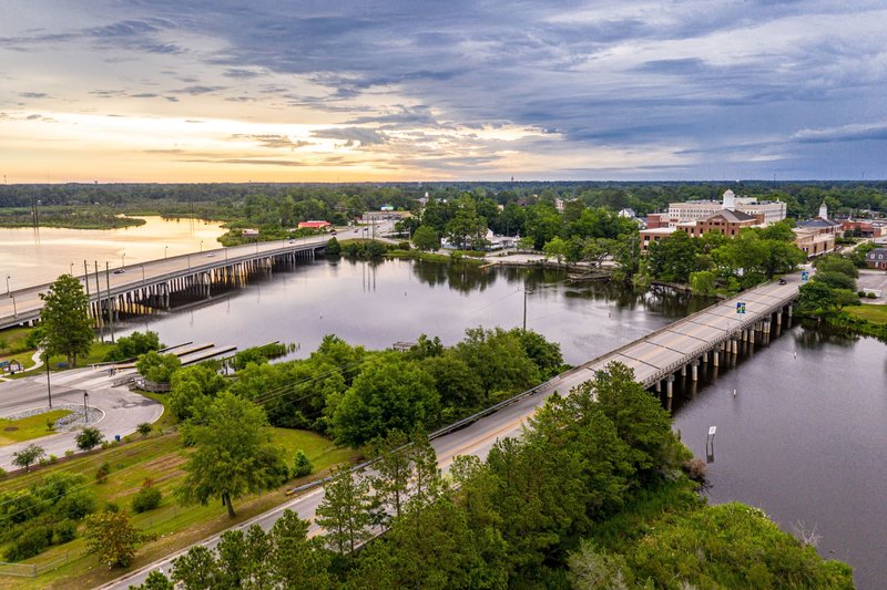 An elevated view of river water, bridges, roads, and town buildings in Jacksonville, NC.