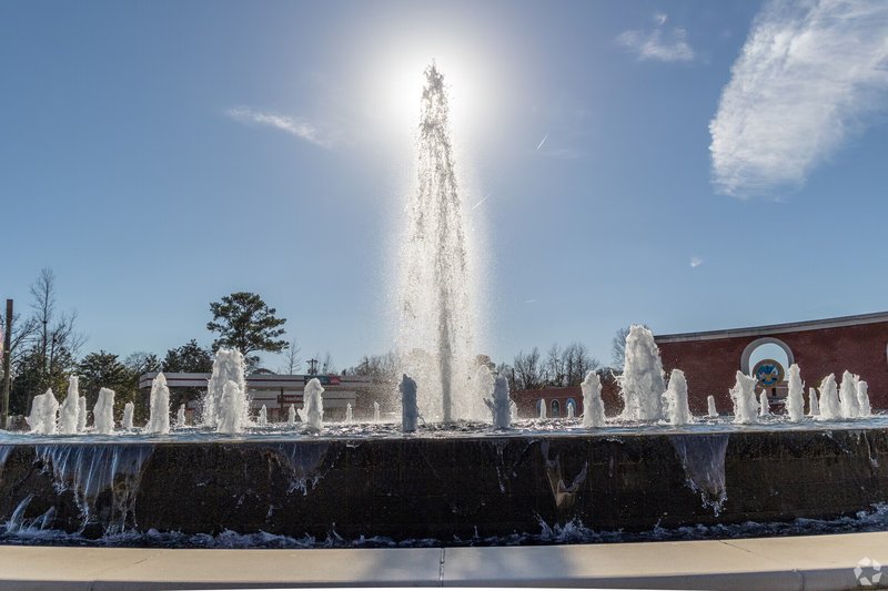 A circular fountain with multiple water jets in front of a brick building in Jacksonville, NC.
