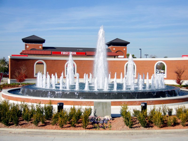 A landscaped circular fountain in front of a commercial building in Jacksonville, NC.